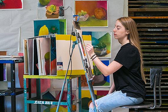 Student painting at easel in art studio classroom